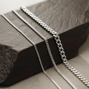 Heavy, medium and fine sterling silver curb chains on draped on wooden beam