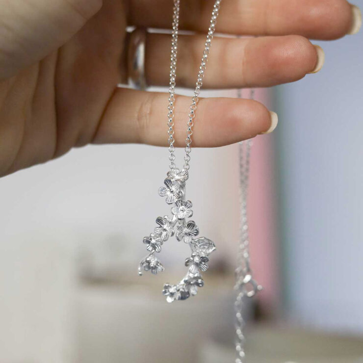 Sterling Silver Forget Me Not Cluster Necklace in models hand