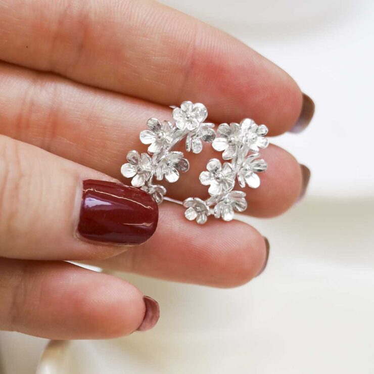 MB118_Sterling Silver Forget Me Not Drop Earrings_6 model holding Sterling Silver Forget Me Not Drop Earrings