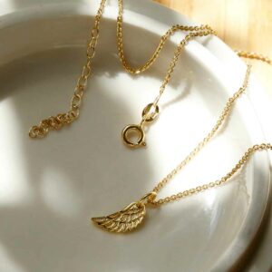 Gold Angel wing Necklace on ceramic background