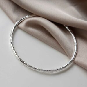 Sterling Silver Textured Bark bangle on beige material