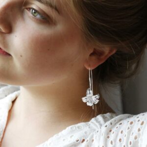 Large silver lily earrings featuring a long silver stem threaded through the ear