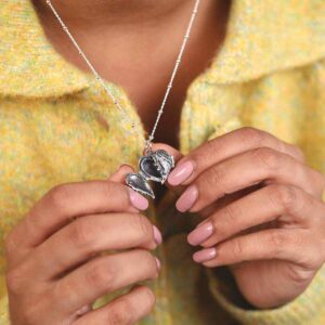 Model in Green Jacket Holding Sterling Silver Love Wings Locket