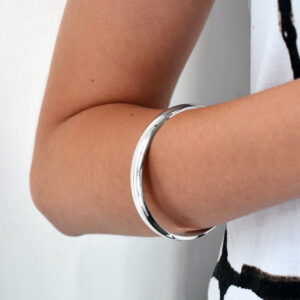 model wearing rounded polished bangle around forearm