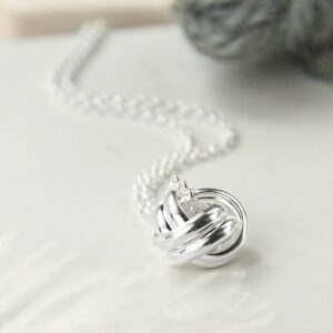 Silver Forever Knot Necklace in focus with Grey Yarn Background