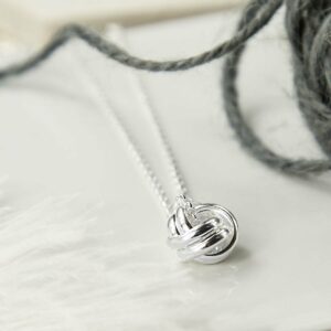 Silver Forever Knot Necklace in focus with Grey Yarn Background