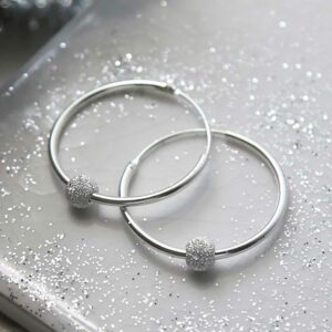 Sterling silver disco ball hoops on sparkly tile background