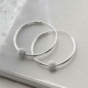 Sterling silver disco ball hoops on tile background