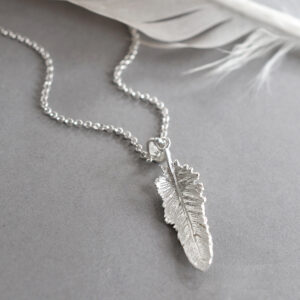 small feather pendant on a grey back ground with feather