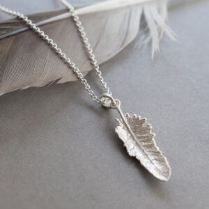 small feather pendant on a grey back ground with feather