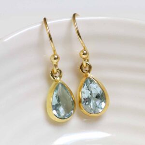 Sterling Silver Gold Plated Dangly Blue Topaz Teardrop Earrings on white dish