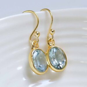 Sterling Silver Gold Plated Dangly Blue Topaz Oval Earrings on white dish