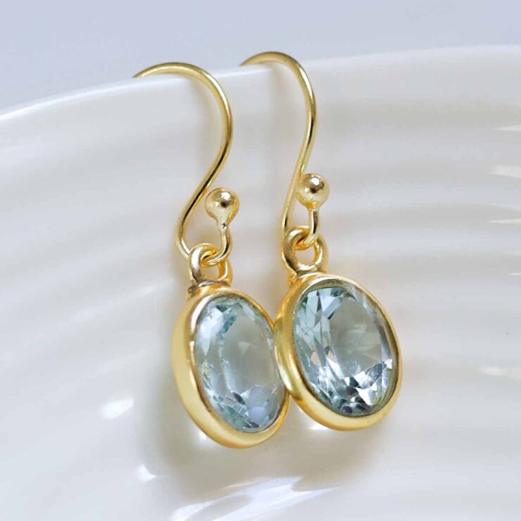 MJ754DG_Sterling Silver Gold Plated Dangly Blue Topaz Oval Earrings_1 Sterling Silver Gold Plated Dangly Blue Topaz Oval Earrings on white dish