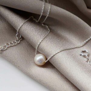 Single Pearl Necklace on silky material background