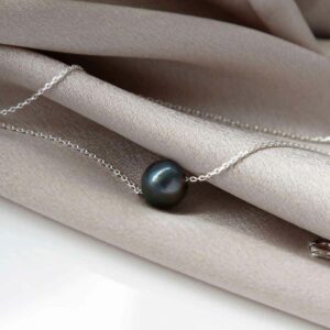 Black fresh water pearl on chain resting on silky material