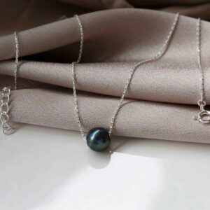 Black fresh water pearl on chain resting on silky material