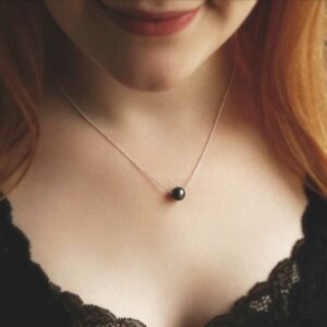 Black fresh water pearl on chain resting on red haired model with black top