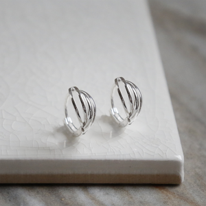 Polished sterling silver braided huggies/ hinged hoop earrings on white background.