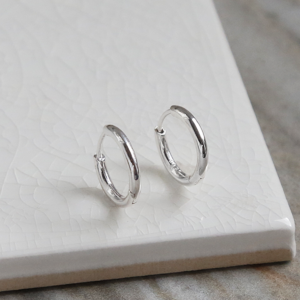 Big polished sterling silver huggies on white background.