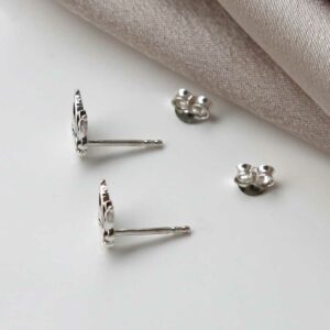 Small silver botanical studs on neutral pink silk background