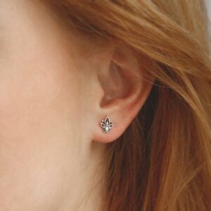 Model with red hair wearing small silver botanical studs