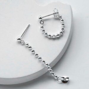 Silver Swinging bead studs, one undone and one fastened on white background with shadows