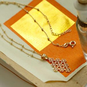 Gold Moroccan Tile Necklace on Orange and Gold Paper background