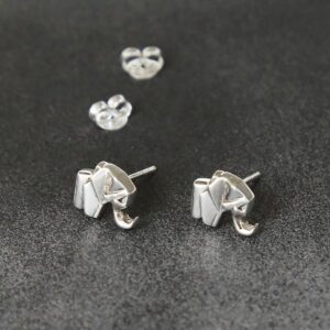 Two silver geometric elephant stud earrings sat on a grey slate coloured material with two silver butterfly backs in the background