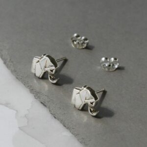 Two silver geometric elephant stud earrings sat on a grey slate coloured material with two silver butterfly backs in the background