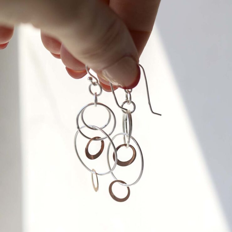 Sterling Silver And Rose Gold Swinging Circles Dangly Earrings being held