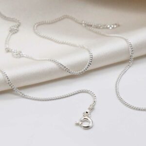 sterling silver fine curb chain strewn on linen