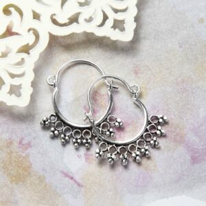 Sterling Silver Temple Hoops Placed on a Pink and yellow watercolour paint background with Cream paper cut out details