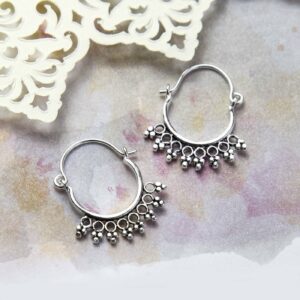 Sterling Silver Temple Hoops Placed on a Pink and yellow watercolour paint background with Cream paper cut out details