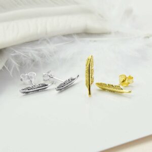 Small Feather Stud on the left, Small Gold feather stud on the right with White ceramic feather and white feather as backgound