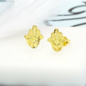 Pair of Gold Hamsa Hand Studs on white tile background and blue and black pattern paper with White Feather