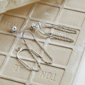 Two way chain Sterling Silver studs, one earring appearing undone on Sandy tile background with canvas