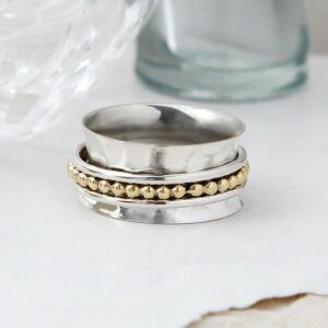 Self care spinner ring on white background, with ripped paper detail and glass vases as background setting