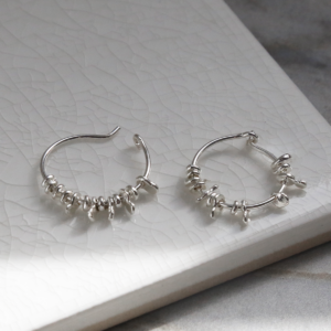 Sterling silver gypsy hoops on white background. one open and one closed.