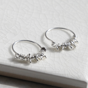 ml918 sterling silver gypsy hoops on white background.  Coin charms catching the light.