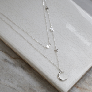 Double layered sterling silver moon and star charm necklace on white background.