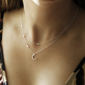 Double layered sterling silver moon and star charm necklace on woman wearing leopard dress..