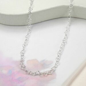 heart shaped wire necklace draped over pink water colour background