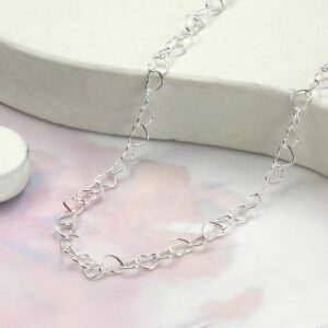 heart shaped wire necklace draped over pink water colour background