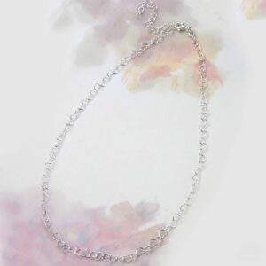 heart shaped wire necklace draped over pink water colour background