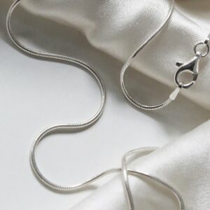 sterling silver fine snake chain necklace strewn on linen