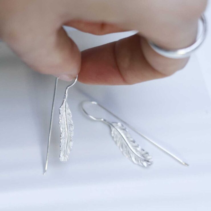 Sterling Silver Feather Drop Earrings in models hand