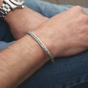 Woven bracelet worn on the wrist of a male, jean background