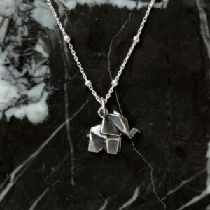 sterling silver origami elephant necklace on marble background