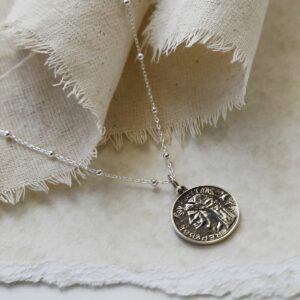 Sterling Silver Roman Head Coin Necklace hanging on linen