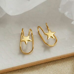 gold plated Sterling Silver Star Ear Cuffs sat on a marble tile with their shadow being cast